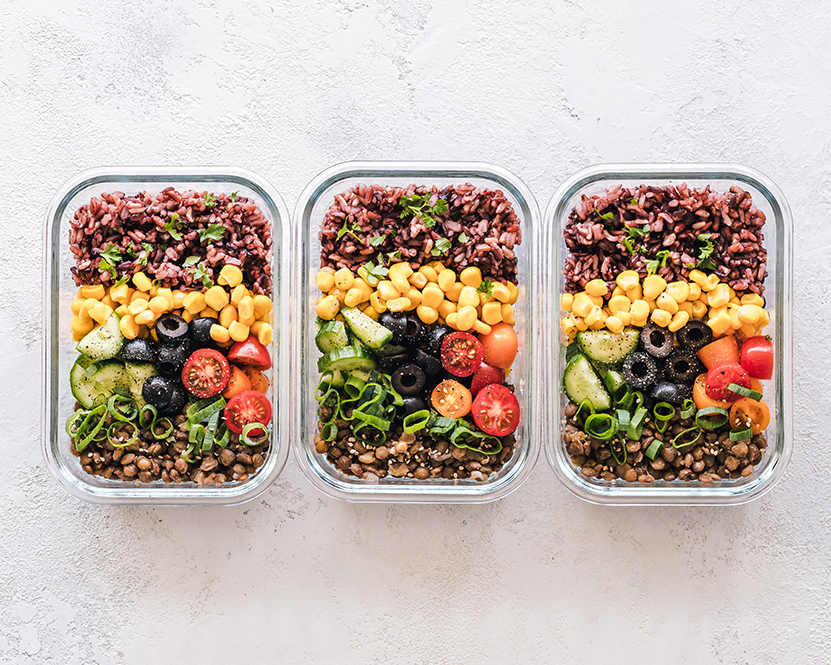 Three healthy meal prep trays of colourful food.