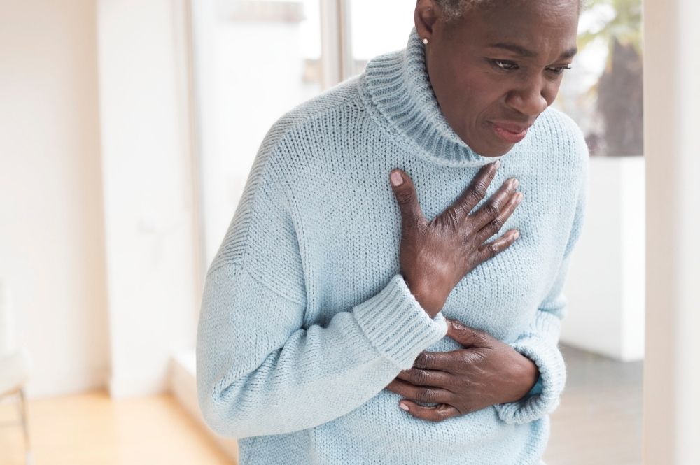 A woman clutches her chest signalling heart health issues.