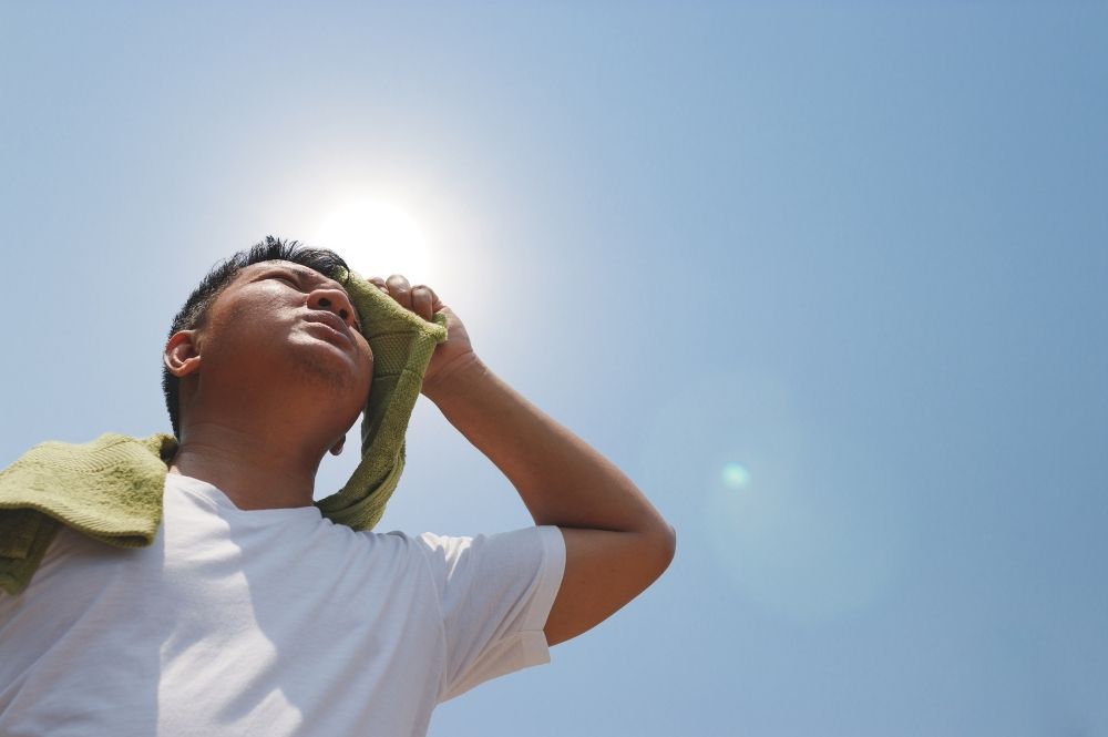 A man stands under a hot sun, he is at risk of developing heat stroke.