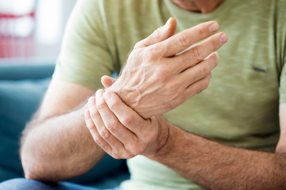 A man holds his wrist, which is in pain due to arthritis.